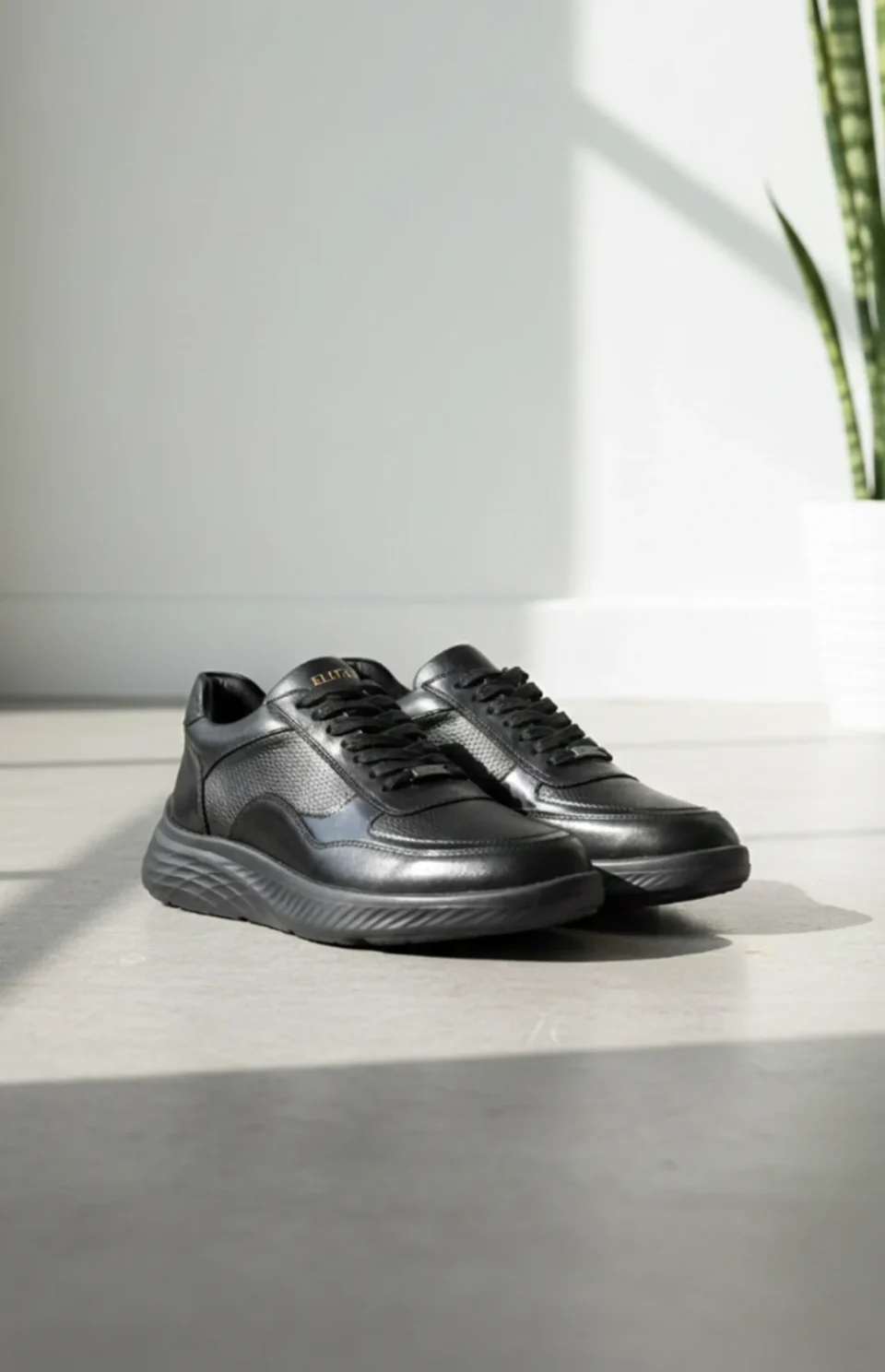 Baskets noires en cuir avec des lacets, présentées sur un sol clair.