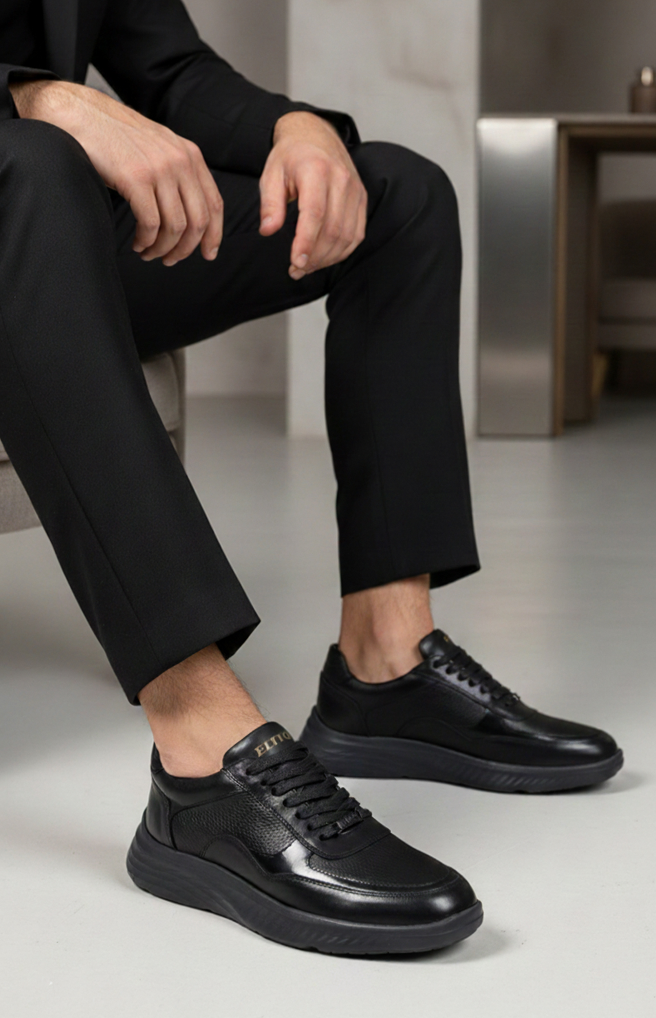 Détail cuir grainé et fiSneakers AXIS noir portées avec costume - Baskets élégantes en cuir noir brillant - Style moderne professionnel confortablenitions premium sneaker AXIS Elito